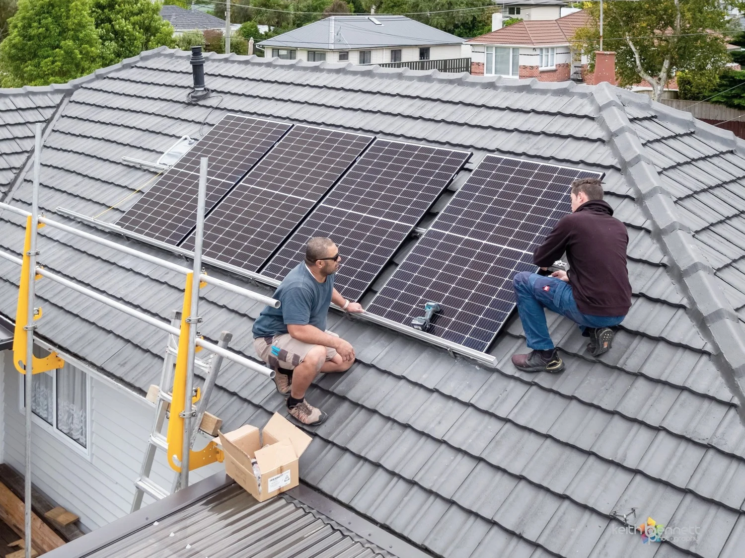 Electricians installing custom solar panels onto a residential home roof.